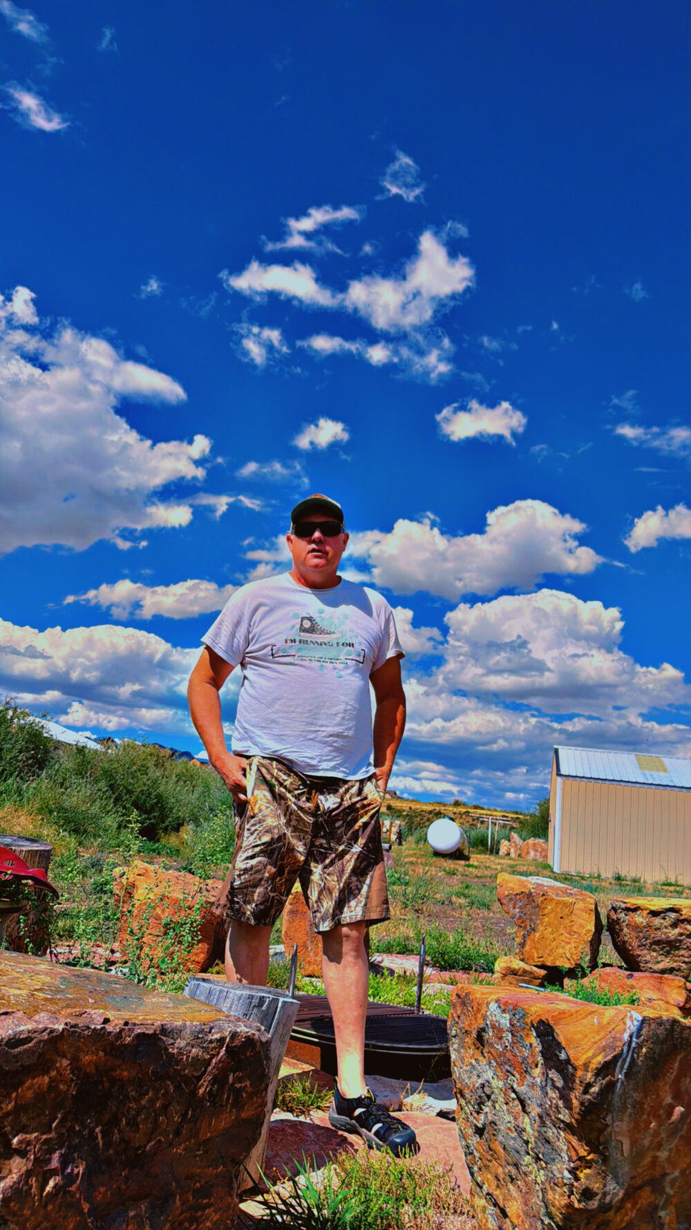 Troy Puls standing on the rocks under a big Wyoming sky wearing his campaign shirt