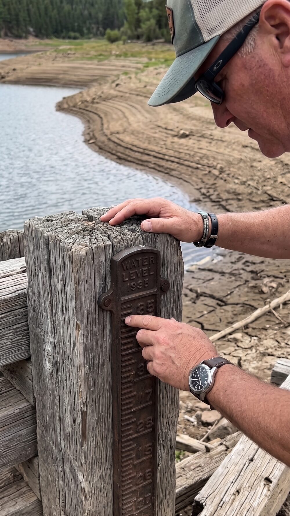 Troy Puls examining a water level gauge marked 1935 at a low Wyoming reservoir